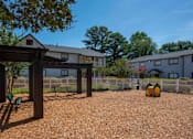 Thumbnail 19 of 20 - A gravel area with a wooden structure and a fence in the background at The Madison Apartments and Townhomes, Lawrenceville, GA