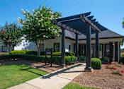 Thumbnail 4 of 20 - A building with a covered walkway entrance surrounded by greenery at The Madison Apartments and Townhomes, Lawrenceville, GA