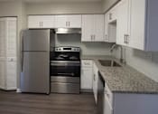 Thumbnail 6 of 20 - A kitchen with a refrigerator, oven, and sink at The Madison Apartments and Townhomes, Lawrenceville, GA, 30044