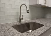 Thumbnail 7 of 20 - A modern kitchen sink with a chrome faucet at The Madison Apartments and Townhomes, Georgia