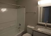 Thumbnail 9 of 20 - A bathroom with a toilet, sink, and bathtub at The Madison Apartments and Townhomes, Lawrenceville, Georgia