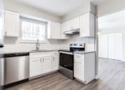 Thumbnail 2 of 27 - A kitchen with white cabinets and a black countertop at Barcelo at East Cobb Apartments, Georgia, 30067