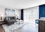 Thumbnail 6 of 27 - A living room with a grey couch, a blue rug, and a painting on the wall at Barcelo at East Cobb Apartments, Marietta, GA, 30067