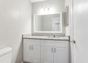 Thumbnail 13 of 27 - A bathroom with a granite countertop and white cabinets at Barcelo at East Cobb Apartments, Marietta, GA, 30067