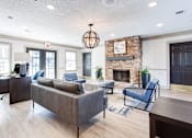 Thumbnail 16 of 27 - A living room with a grey couch and a fireplace at Barcelo at East Cobb Apartments, Marietta