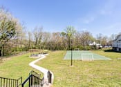 Thumbnail 19 of 27 - A green grassy area with a basketball court and a house in the background at Barcelo at East Cobb Apartments, GA, 30067