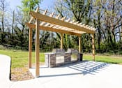 Thumbnail 20 of 27 - A wooden pergola structure is situated over a stone bench in a park at Barcelo at East Cobb Apartments, Marietta, GA