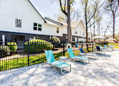 Thumbnail 23 of 27 - A white building with a black fence and blue chairs in front at Barcelo at East Cobb Apartments, Marietta, GA