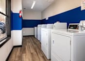 Thumbnail 25 of 60 - a row of washers and dryers in a room with blue and white walls at Cleo Apartments, Athens, 35611