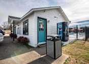 Thumbnail 26 of 60 - a small white building with a blue door and a trash can at Cleo Apartments, Alabama, 35611