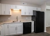 Thumbnail 2 of 60 - a kitchen with white cabinets and black appliances at Cleo Apartments, Athens, AL