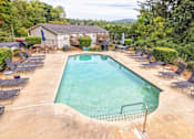 Thumbnail 13 of 14 - A large outdoor swimming pool surrounded by lounge chairs at Overlook Club Apartments, Cummings, Georgia