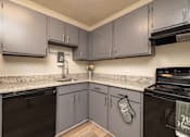 Thumbnail 7 of 14 - A kitchen with grey cabinets and a black stove top oven at Overlook Club Apartments, Georgia