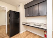 Thumbnail 8 of 14 - A black fridge in a kitchen with wooden floors and black cabinets at Overlook Club Apartments, Cummings