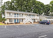 Thumbnail 9 of 14 - A two-story building with a blue car parked in front at Overlook Club Apartments, Cummings, GA