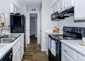Thumbnail 12 of 16 - a kitchen with black appliances and white cabinets at The Davis Apartments, Huntsville  