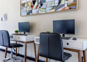 Thumbnail 14 of 16 - two desks with two monitors and two chairs in a room at The Davis Apartments, Alabama, 35816