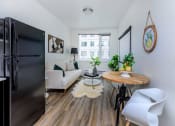 Thumbnail 43 of 57 - a small living room with a couch and a table with a chair at Jefferson Yards, Tacoma, WA