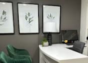 Thumbnail 3 of 22 - A white desk with a black chair and three framed pictures on the wall.