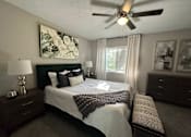 Thumbnail 9 of 22 - A bedroom with a bed, nightstand, and a ceiling fan.