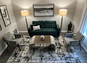 Thumbnail 7 of 22 - A living room with a green couch, two chairs, a coffee table, and a rug.