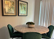 Thumbnail 5 of 22 - A dining table with four chairs and two pictures on the wall.