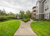 Thumbnail 39 of 48 - A walkway leads through a grassy area to a building.