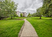 Thumbnail 42 of 48 - A pathway leads through a grassy area towards a building.