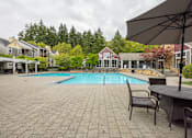 Thumbnail 43 of 48 - A patio with a table and chairs overlooking a pool.