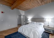 Thumbnail 17 of 27 - A bedroom with a white bed and a wooden ceiling.