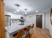 Thumbnail 16 of 27 - A kitchen with a white countertop and wooden chairs.