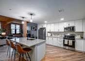 Thumbnail 15 of 27 - A kitchen with white cabinets and a wooden floor.