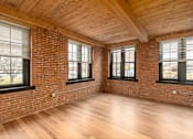 Thumbnail 11 of 27 - A room with wooden floors and brick walls has three windows.
