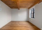 Thumbnail 12 of 27 - A room with wooden floors and a window.