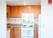 Thumbnail 15 of 21 - A kitchen with wooden cabinets and white appliances.