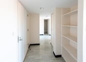 Thumbnail 16 of 21 - A long hallway with a tile floor and white walls.