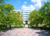 Thumbnail 7 of 17 - a large white building with a red brick walkway in front of it