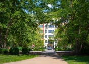 Thumbnail 11 of 17 - a walkway with trees in the foreground and a building in the background