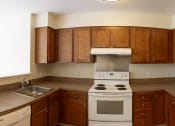 Thumbnail 16 of 17 - a kitchen with wooden cabinets and white appliances