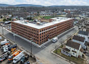 Thumbnail 19 of 27 - A large red brick building with a parking lot in front of it.