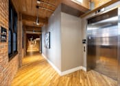Thumbnail 24 of 27 - A long hallway with wood floors and a metal elevator.
