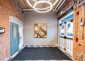 Thumbnail 9 of 27 - A hallway with a blue door and a painting on the wall.