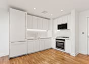 Thumbnail 33 of 33 - A kitchen with white cabinets and a wooden floor.