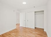 Thumbnail 27 of 33 - a bedroom with white walls and wood flooring and sliding closet doors