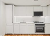Thumbnail 18 of 33 - a kitchen with white cabinets and a stove and a sink