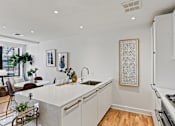 Thumbnail 3 of 33 - A modern kitchen with white cabinets and a large island.