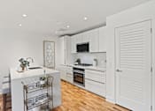 Thumbnail 4 of 33 - A kitchen with white cabinets and a white island with a sink.