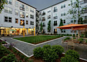 Thumbnail 2 of 6 - a courtyard with tables and chairs in front of an apartment building