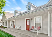 Thumbnail 13 of 17 - A house with a red door and white chairs on the porch.