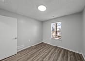 Thumbnail 8 of 17 - A room with a window and wooden flooring.